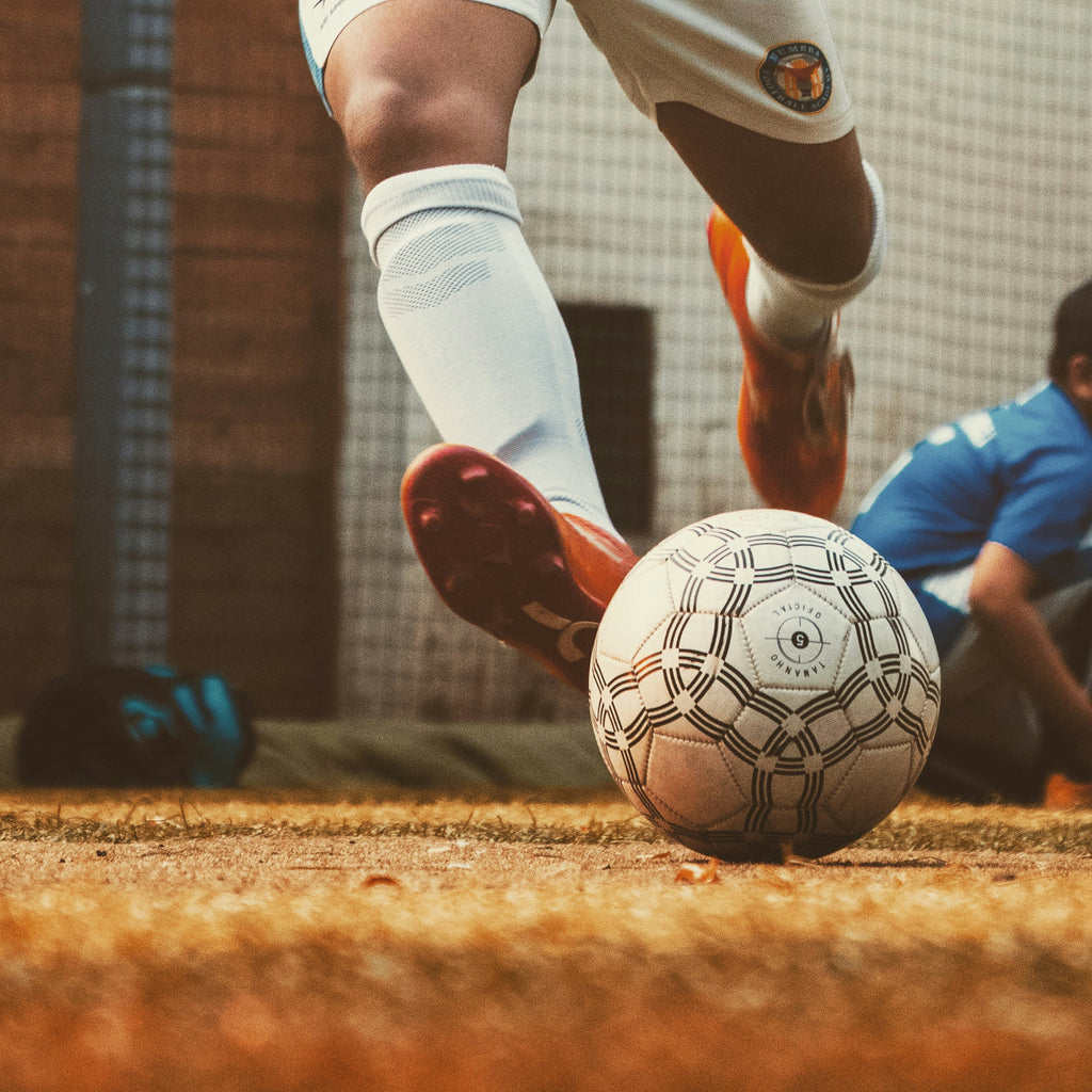 Calciatore che calcia il pallone con plantare sportivo biomeccanico MEDERE per calcio